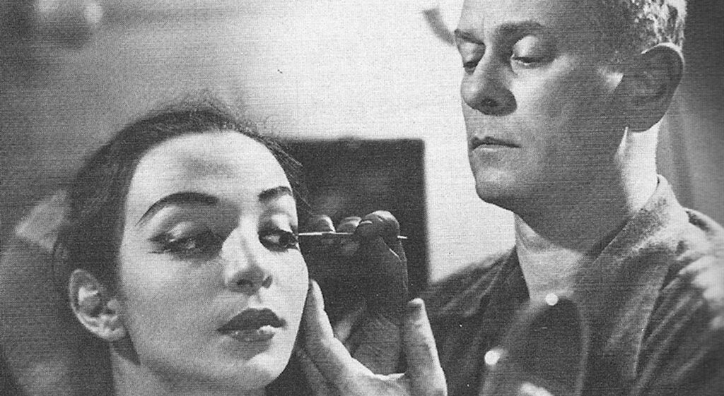 Lester Horton applying makeup to a dancer in black and white.