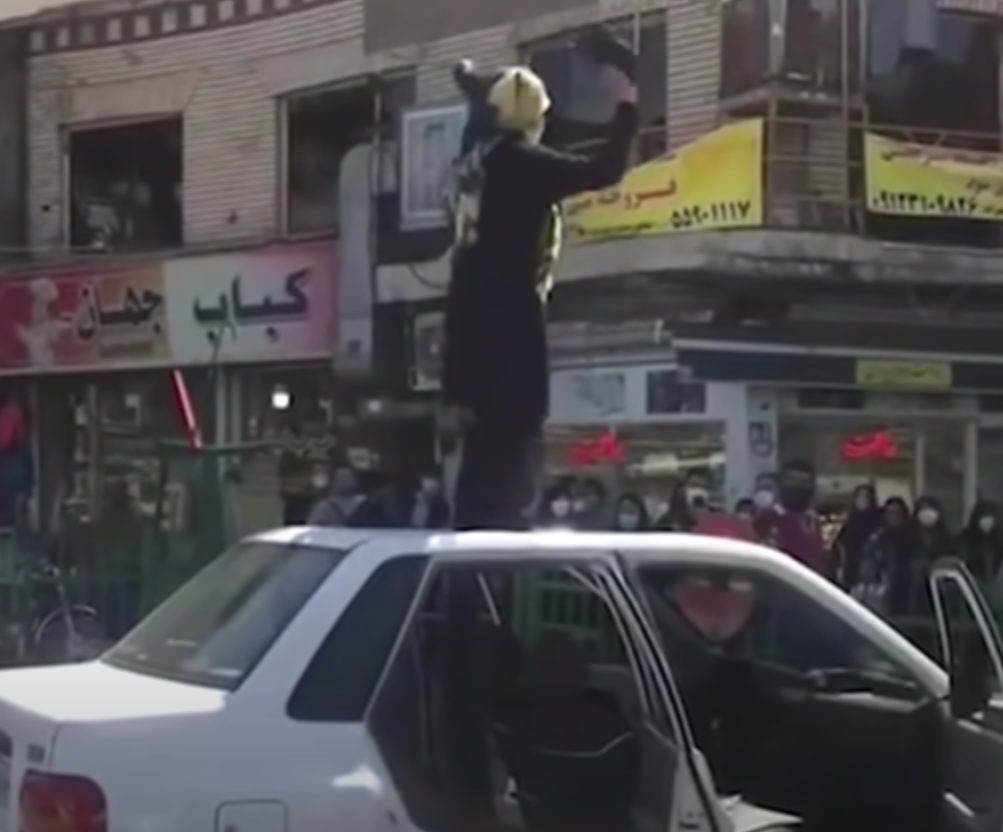 Women dances on top of a car in Iran.